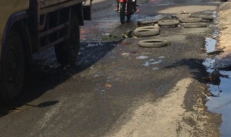 Jalan Raya Bintara Raya Bekasi Barat yang rusak parah ditambal secara darurat oleh warga dengan ban bekas