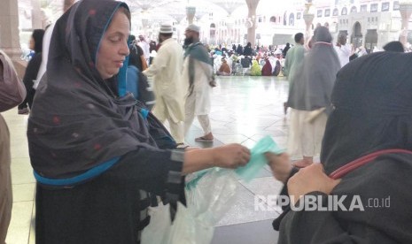 Jamaah asal India membagikan masker gratis kepada jamaah haji di Masjid Nabawi jelang maghrib, Selasa (15/8). 