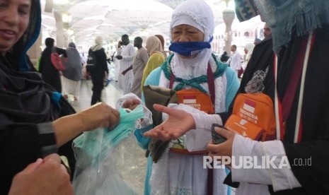 Jamaah asal India membagikan masker gratis kepada jamaah haji di Masjid Nabawi jelang maghrib, Selasa (15/8). 