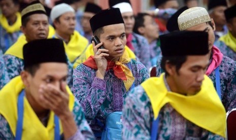   Jamaah calon haji asal Banten menelepon keluarganya saat berada di ruang serba guna, Asrama Haji Pondok Gede, Jakarta, Jumat (27/9).  (Republika/Agung Supriyanto)