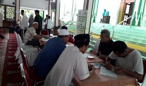 Jamaah menyerahkan zakat kepada petugas zakat Masjid Agung Sunda Kelapa.