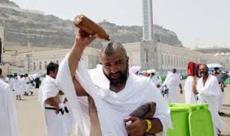 Jamaah menyiramkan air untuk mengurangi sangatan panasnya suhu udara di Makkah.