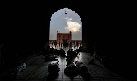 Jamaah Muslim India beristirahat berbaring menunggu waktu berbuka di Masjid Jama, New Delhi, India.