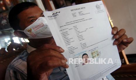 Jemaah Calon Haji Wasnadi (62) menunjukan bukti pelunasan pembayaran ibadah haji 