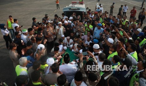 Jemaah dan petugas bandara memanjatkan doa di dekat peti berisi jenazah Ustad Arifin Ilham yang baru tiba dari Penang, Malaysia di Bandara Halim Perdanakusuma, Jakarta Timur, Kamis (23/5/2019).