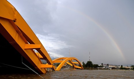 Jembatan kuning yang rusak akibat gempa dan tsunami dengan latar belakang pelangi di Kawasan Lere, Palu, Sulawesi Tengah, Minggu (14/10).