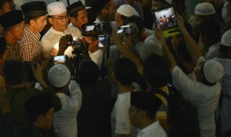 Joko Widodo (kedua kiri atas) menyalami jamaah usai menunaikan ibadah Salat Isya berjamaah yang dilanjutkan Salat Tarawih malam ketiga di bulan Ramadan 1435 H 