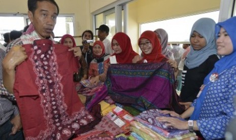  Joko Widodo (kiri) melihat hasil kerajinan kain songket ketika berkunjung ke sentra usaha mikro, kecil, dan menengah (UMKM) Tuan Kentang, di Kelurahan Tuan Kentang, Kecamatan Seberang Ulu Satu, Palembang, Sumatera Selatan, Rabu (25/6). 