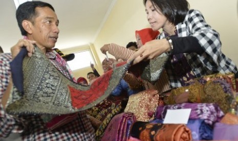 Joko Widodo (kiri) melihat hasil kerajinan kain songket ketika berkunjung ke sentra usaha mikro, kecil, dan menengah (UMKM) Tuan Kentang, di Kelurahan Tuan Kentang, Kecamatan Seberang Ulu Satu, Palembang, Sumatera Selatan, Rabu (25/6). 