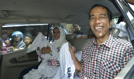  Jokowi dan istrinya, Iriana membagikan kaus ketika berkampanye mengunjungi kawasan Pasar Kota, Gresik, Jawa Timur, Ahad (29/6).