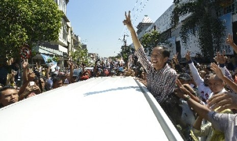  Jokowi mengacungkan salam dua jari kepada warga ketika berkunjung ke kawasan Pasar Kota, Gresik, Jawa Timur, Ahad (29/6).