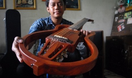 JOMBANG -- GITAR NILON 12 DAWAI. Bayu Angga Pridahastama (24) mahasiswa Universitas Negeri Surabaya, jurusan Sendratasik, Seni Musik, mayor gitar klasik semester 8 menunjukan gitar klasik elektrik dua belas dawai hasil karya skripsinya yang mempunyai dua k