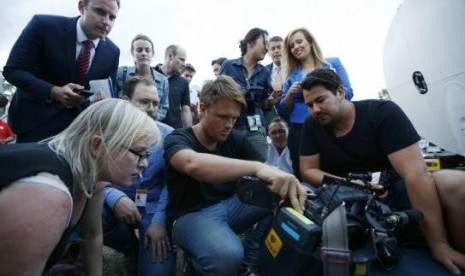 Journalists look at the monitor of a television camera crew who shot footage onboard a P-3 Orion aircraft of objects in the southern Indian Ocean, on March 24, 2014.