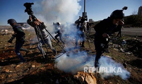 Jurnalis berlarian menghindari gas air mata yang ditembakkan tentara Israel di Kota Ramallah, Tepi Barat, Palestina, Jumat (8/12)