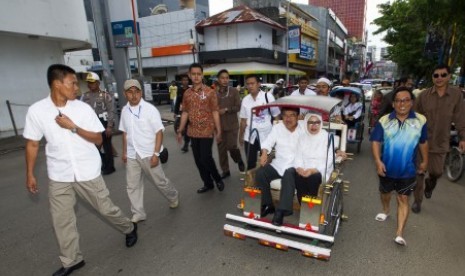 Jusuf Kalla, bersama istri Ny Mufidah Kalla, menggunakan sarana transportasi becak saat akan menggelar pertemuan dengan sejumlah tokoh di Pantai Losari, Makassar, Sulsel, Kamis (12/6). 