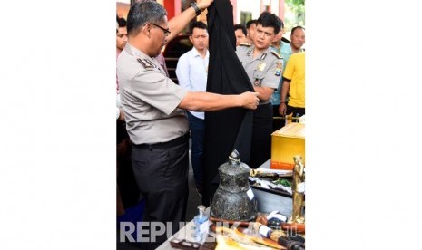 Kabid Humas Polda Jawa Timur Kombes Pol Raden Prabowo Argo Yuwono (kiri) menunjukkan barang bukti berupa jubah dari tersangka penipu Dimas Kanjeng Taat Pribadi ketika ungkap kasus di Mapolda Jawa Timur, Jumat (7/10). 