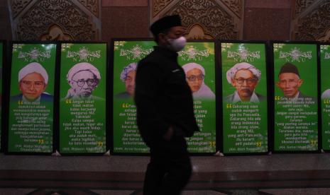 Panitia Selaraskan Materi Jelang Muktamar ke-34 NU. Kader NU melintas di dekat sejumlah foto para tokoh pendiri Nahdlatul Ulama saat diselenggarakannya Rapat Harian Syuriyah dan Harian Tanfidziyah Nahdlatul Ulama di Gedung PBNU, Jakarta, Selasa (7/12/2021). Rapat yang masih berlangsung hingga malam hari tersebut digelar untuk memutuskan penetapan jadwal Muktamar ke-34 Nahdlatul Ulama. 