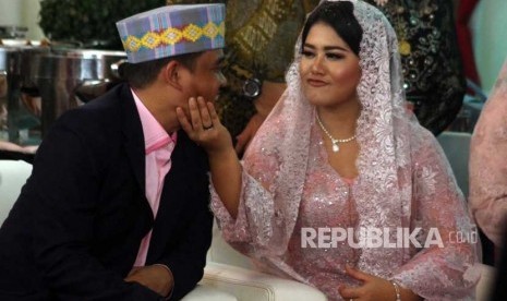 Kahiyang Ayu (kanan) dan Bobby Nasution saling bercanda disela upacara penabalan marga di Medan, Sumatera Utara, Selasa (21/11).