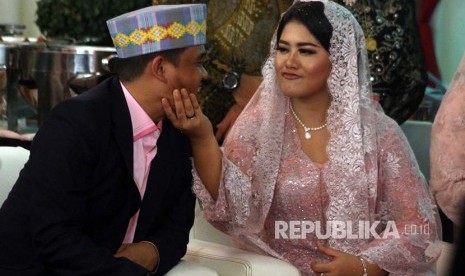 Kahiyang Ayu (kanan) dan Bobby Nasution saling bercanda disela upacara penambalan marga di Medan, Sumatera Utara, Selasa (21/11). Kahiyang Ayu, yang telah menjadi istri Bobby Afif Nasution itu resmi bermarga Siregar setelah menjalani upacara adat penganugerahan marga.