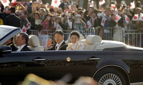 Kaisar Jepang Naruhito dan Permaisuri Masako melambaikan tangan kepada warga saat parade kekaisaran di Tokyo, Ahad (10/11).