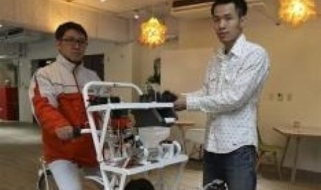 Kamm Kai-yu (right), a co-founder of boutique design studio Fabraft, displays a bicycle with a 3D printer installed in front, in Taipei March 13, 2014.