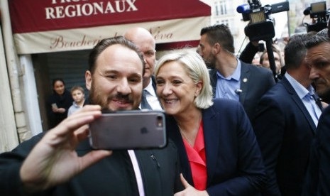 Kandidat presiden Prancis dari kubu sayap ekstrem kanan Marine Le Pen berswafoto saat meninggalkan markas Partai Front National di Paris, Ahad, 7 Mei 2017.