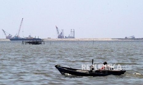  Kapal kayu melintas berlatar belakang pembangunan reklamasi pantai pulau G, Muara Baru Jakarta, Rabu (6/4). 