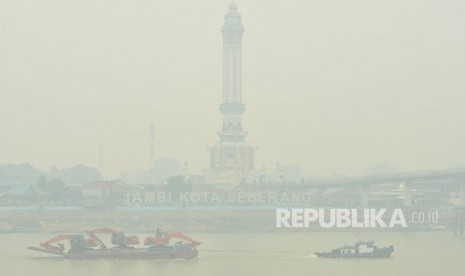 Kapal tongkang membawa alat berat melintasi Sungai Batanghari yang diselimuti kabut asap dari karhutla di Jambi, Sabtu (21/9/2019).