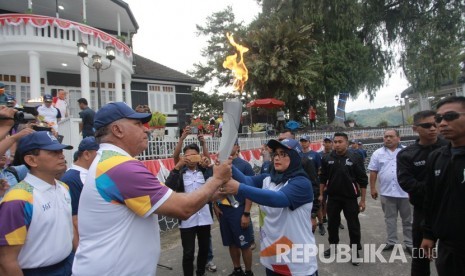 Kapolda Sumatera Utara Irjen Pol Paulus Waterpauw (kedua kiri) didampingi Bupati Simalungun JR Saragih (kiri) menyerahkan obor Asian Games 2018 kepada mantan atlet Pencak Silat juara dunia Dahliana (ketiga kanan) di depan Pesanggrahan Bung Karno, di Parapat, Simalungun, Danau Toba, Sumatera Utara, Rabu (1/8).