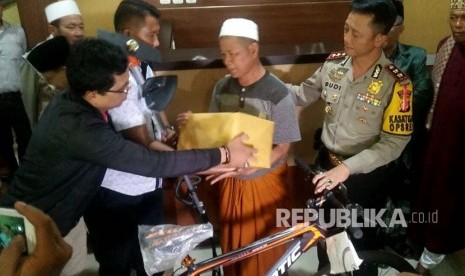 Kapolres Garut, AKBP Budi Satria Wigunna (kanan) menyerahkan bantuan kepada  YR marbot Masjid Agung Istiqomah Kecamatan Pameungpeuk tersangka kasus laporan palsu di Mapolres Garut. 