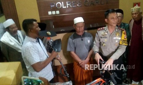 Kapolres Garut, AKBP Budi Satria Wigunna (kanan) menyerahkan bantuan kepada  YR marbot Masjid Agung Istiqomah Kecamatan Pameungpeuk tersangka kasus laporan palsu di Mapolres Garut. 