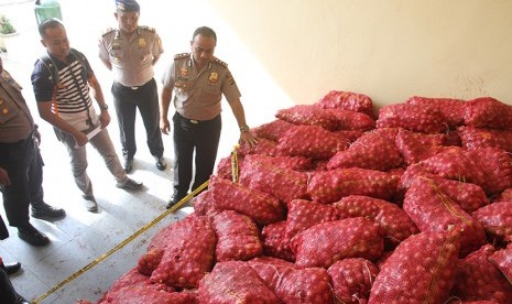 Kapolres Kota Langsa AKBP Iskandar Za Sik (kanan) memperlihatkan bawang merah ilegal yang disita di Mapolres Kota Langsa, Langsa, Aceh, Senin (30/5).