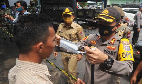 Kapolresta Padang AKBP Imran Amir (kanan) memasangkan masker kepada seorang warga yang sudah menjalani sanksi sosial menyapu jalan karena tidak menggunakan masker di Jalan Bundo Kanduang, Padang, Sumatera Barat, Senin (21/9/2020). Pemkot Padang mulai menerapkan aturan Perda Adaptasi Kebiasaan Baru (AKB) berupa sanksi sosial, denda dan kurungan penjara bagi warga yang tidak mematuhi protokol pencegahan COVID-19 di antaranya wajib menggunakan masker saat di luar rumah.