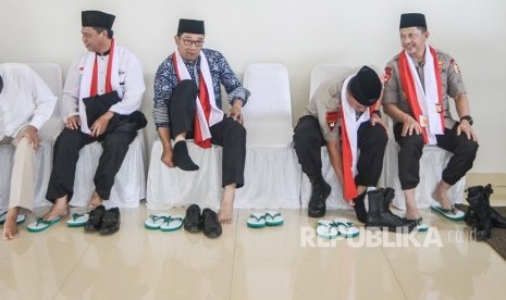 Kapolri Jenderal Pol Tito Karnavian (kanan) bersama Kapolda Jabar Irjen Pol Agung Budi Maryoto (kedua kanan), Gubernur Jawa Barat Ridwan Kamil (kedua kiri) dan mantan Kapolda Jabar Anton Charliyan (kiri) melepas alas kakinya untuk melaksanakan Salat Jumat seusai silaturahmi Kamtibmas di Mapolda Jabar, Bandung, Jawa Barat, Jumat (15/2/2019). 