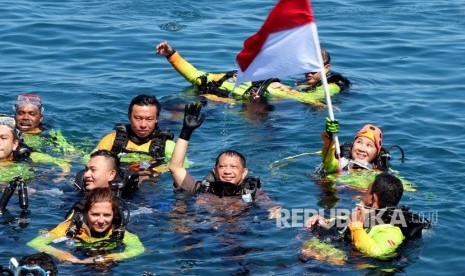 Kapolri Jendral Pol. Tito Karnavian (tengah) bersama istri Ny. Tri Tito Karnavian (mengibarkan bendera) saat naik ke permukaan usai penyelaman massal di kawasan pantai Megamas, Manado, Sulawesi Utara, Sabtu (3/8/2019). 