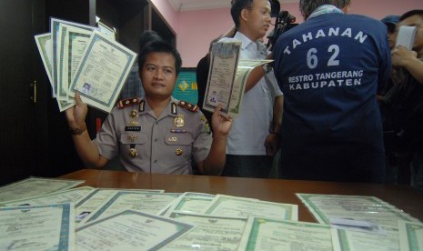  Kapolsek Pd Aren Kompol Hafidz Herlambang menunjukan barang bukti sejumlah ijazah palsu dan juga seorang pelaku Santoso alias Santosa saat gelar perkara di Mapolsek pd Aren, Tangerang Selatan, Selasa (26/3). 