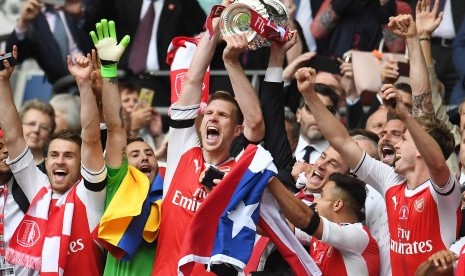 Kapten Arsenal, Per Mertesacker mengangkat trofi Piala FA setelah timnya berhasil mengalahkan Chelsea pada laga final di Stadion Wembley, Ahad (28/5) dini hari WIB.