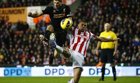 Kapten Liverpool, Steven Gerrard, berebut bola dengan striker Stoke City, Jonathan Walters, pada partai lanjutan Liga Primer Inggris.