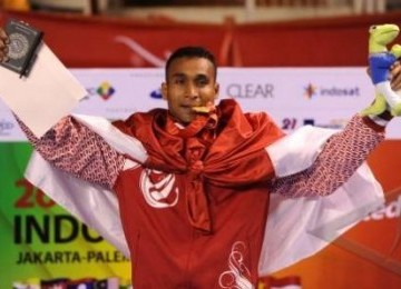 Karateka Indonesia, Umar Syarief, menggigit medali emas saat upacara pemberian medali nomor Kumite +84kg putra SEA Games XXVI di Tennis Indoor Senayan, Jakarta, Sabtu (12/11).