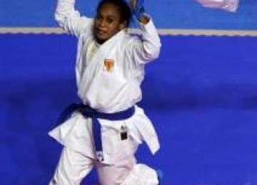 Karateka putri Indonesia, Yulanda Asmuruf, membentangkan bendera Merah Putih setelah memenangkan laga final nomor kumite +68kg putri SEA Games XXVI di Tennis Indoor Senayan, Jakarta, Minggu (13/11). 