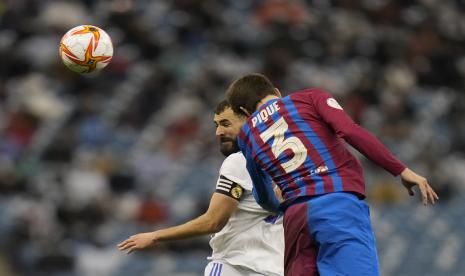 Karim Benzema dari Real Madrid menyundul bola di depan Gerard Pique dari Barcelona selama pertandingan sepak bola semi final Piala Super Spanyol antara Barcelona dan Real Madrid di stadion King Fahd di Riyadh, Arab Saudi, Kamis, 13 Januari 2022.