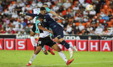 Karim Benzema dari Real Madrid (tengah atas) menyundul bola untuk mencetak gol kedua timnya selama pertandingan sepak bola La Liga Spanyol antara Valencia dan Real Madrid di stadion Mestalla di Valencia, Spanyol, Ahad (19/9).