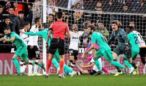 Karim Benzema saat mencetak gol ke gawang Valencia, Ahad Malam.