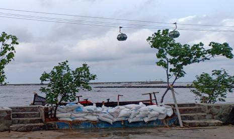 Karung berisi pasir ditempatkan di tembok yang bocor saat rob menerjang kawasan Taman Impian Jaya Ancol, Jakarta Utara, Selasa (7/12).