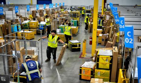 Karyawan Amazon memuat paket ke kereta sebelum dimasukkan ke truk untuk didistribusikan untuk acara tahunan Prime Day Amazon di stasiun pengiriman DAX7 Amazon pada Selasa, 16 Juli 2024, di South Gate, California.