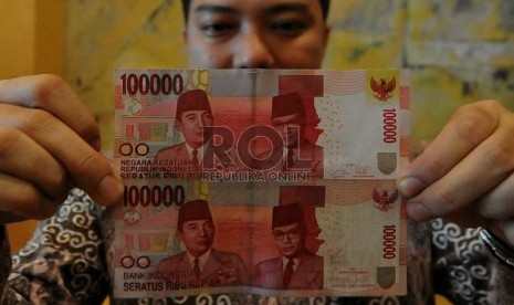 Karyawan Bank Indonesia memerlihatkan uang kertas pecahan Rp. 100.000 baru (atas) dan lama (bawah) usai launching uang tersebut di Bank Indonesia,Jakarta, Senin (18/8). (Republika/Prayogi)