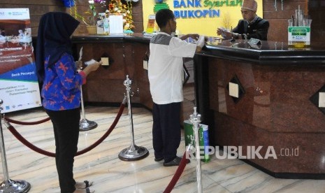  Karyawan melayani nasabah di Bank Syariah Bukopin, Jakarta, Rabu (11/1).