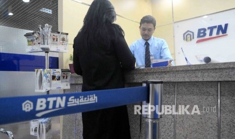  Karyawan melayani nasabah di banking Hall bank BTN Syariah, Jakarta, Selasa (24/1).