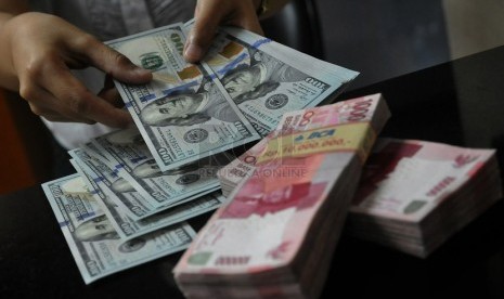 Karyawan melayani penukaran Dollar Amerika di salah satu jasa penukaran valuta asing di Jakarta, Kamis (2/10).(Republika/Prayogi) 