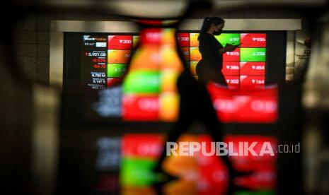 Karyawan melintas di dekat layar monitor pergerakan Indeks Harga Saham Gabungan (IHSG) di Bursa Efek Indonesia, Jakarta, Selasa (11/5). IHSG menguat 0,69 persen ke level 5.800,19 setelah sebelumnya dibuka melemah di level 5.759,63. 